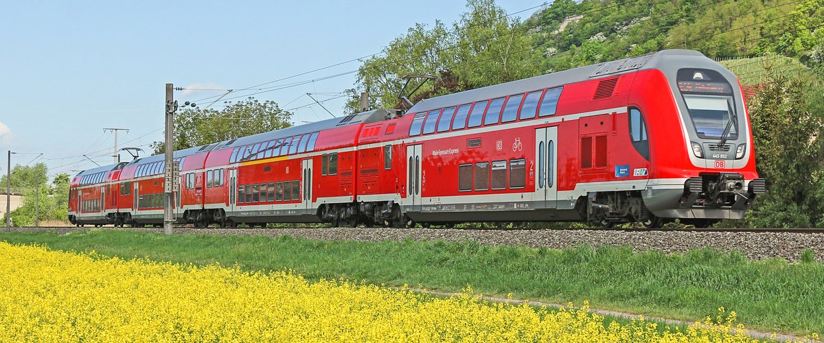 Ein roter Regionalzug der Deutschen Bahn fährt durch die Natur vorbei an einem gelb-blühenden Rapsfeld. | © DB AG / Claus Weber