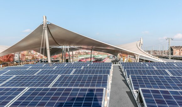 Mehrere Reihen an Solar Panels auf dem Dach eines Bahnhofes.