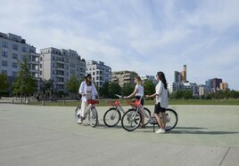 Drei Frauen begrüßen sich in einem Park, jede hat ein Fahrrad der Call a Bike-Initiative dabei.