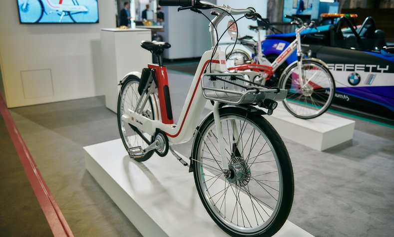 The new prototype at the GREENTECH FESTIVAL 2020, with a first-generation bike in the background.