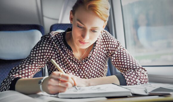 Eine Geschäftsreisende arbeitet während ihrer Fahrt in der Bahn.