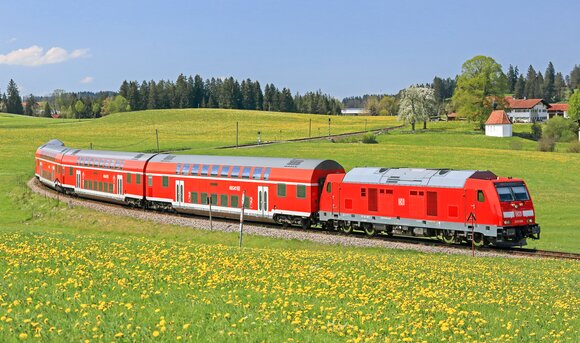 Ein Zug der Deutschen Bahn fährt durch eine blühende Landschaft.