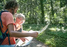 Ein Pärchen orientiert sich mit einer Landkarte auf seiner Wanderung durch der Natur.