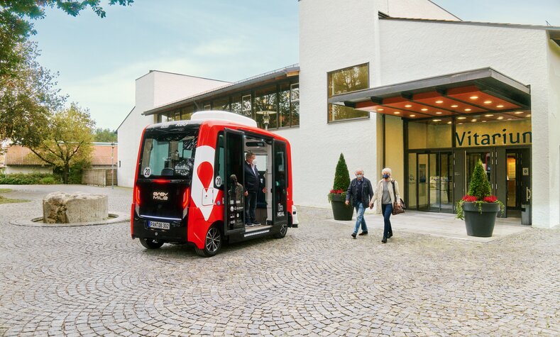 Zwei Menschen treten aus dem Vitarium in Bad Birnbach und gehen auf ein E-Shuttle zu.