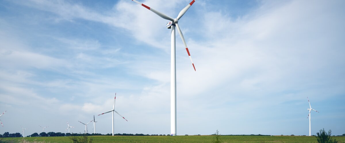 Windräder stehen auf einem Feld neben einer Gleisanlage. | © DB AG / Faruk Hosseini