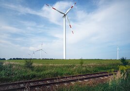 Wind turbines in a field beside a rail line.