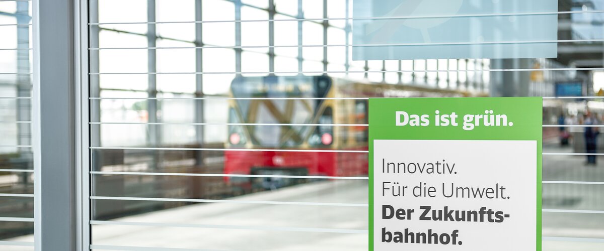 Am Bahnhof Südkreuz hängt das Signet für die Maßnahme Zukunftsbahnhof mit der Botschaft "Innovativ. Für die Umwelt. Der Zukunftsbahnhof.". | © DB AG / Faruk Hosseini