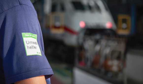 Ein Umwelthelfer trägt ein grünes Signet und ist in einem DB-Werk direkt vor Ort.