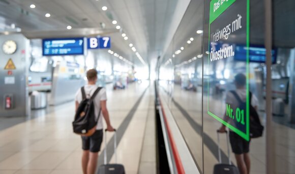 Ein Urlauber mit Rollkoffer ist an einem Bahngleis unterwegs.