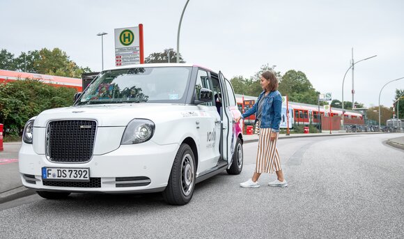 Eine junge Frau steigt an einer Bahnstation in ein Ioki-Shuttle.