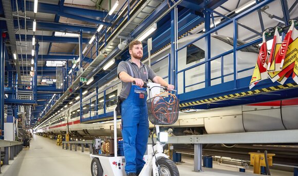 Ein Mitarbeiter ist mit einem E-Scooter im Werk unterwegs. 