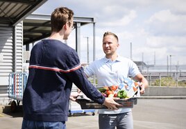 Ein DB-Mitarbeiter übergibt einen Korb mit Lebensmittelspenden an einen Mitarbeiter der Tafel. 