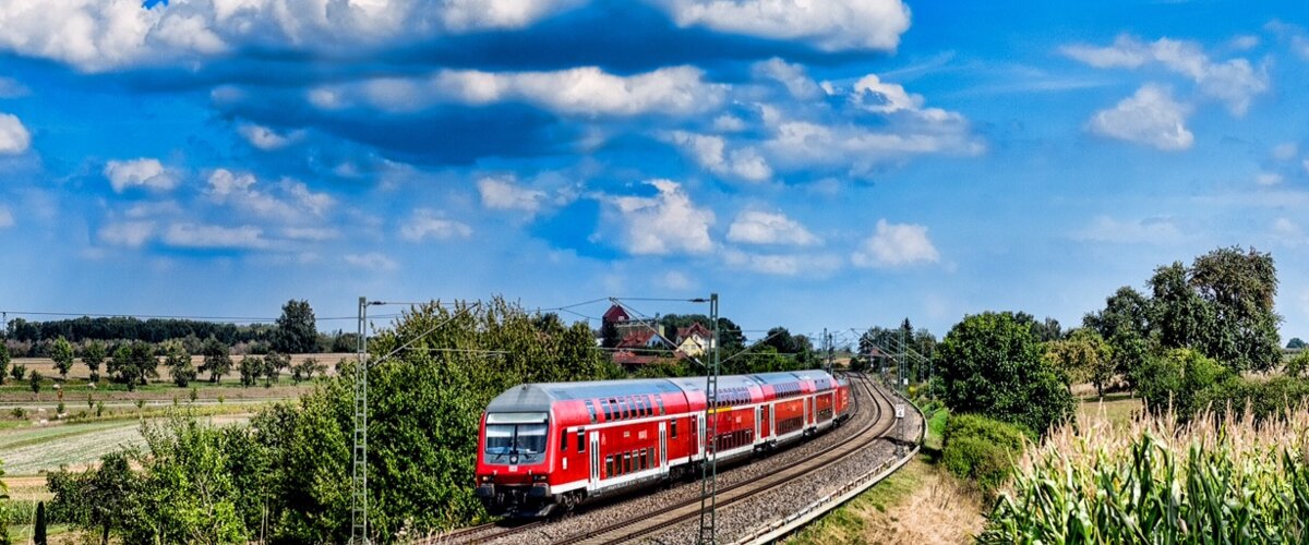 Ein Zug der Deutschen Bahn fährt vorbei an Feldern durch die Natur.  | © Andre Bull