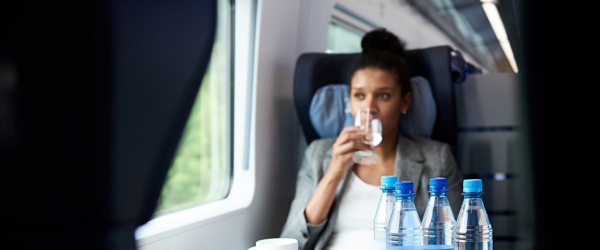 In einem DB-Zug trinkt eine Reisende Wasser aus einer share-Flasche. | © DB AG / Faruk Hosseini