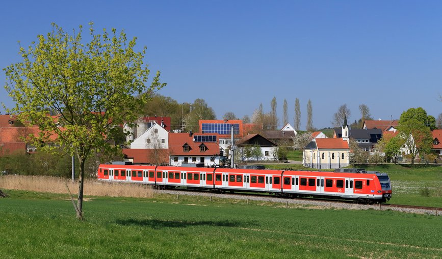 Rote S-Bahn fährt an Ortschaft vorbei