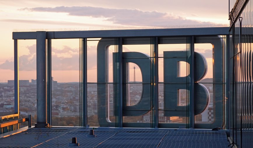 Sonnenuntergang in Berlin am Bahntower, das Deutsche Bahn-Logo ist im Fokus im Hintergrund ist die Stadt zu sehen.