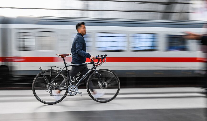 Ein Mann schiebt ein Fahrrad über einen Bahnsteig