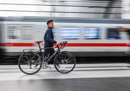 Ein Mann schiebt ein Fahrrad über einen Bahnsteig