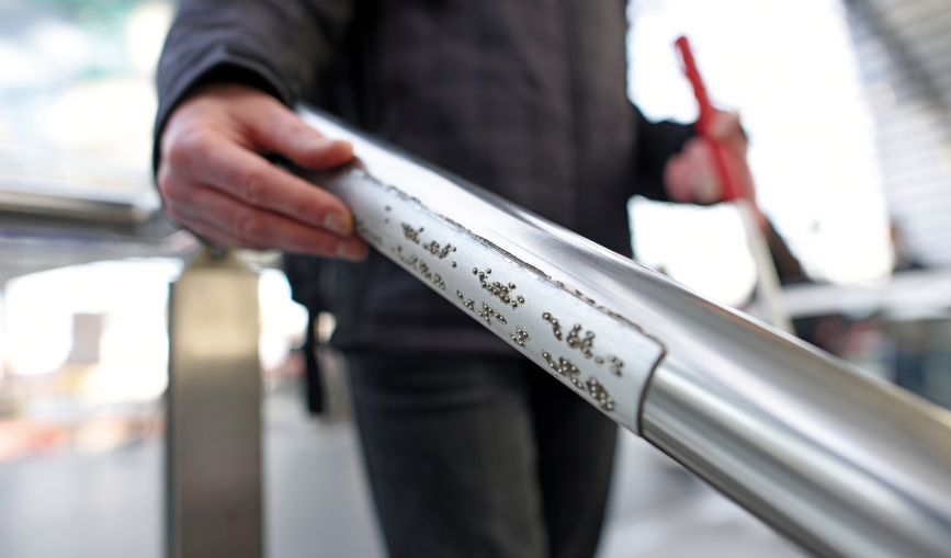 Mann greift nach Geländer mit Taktiles Leitsystem in Berlin