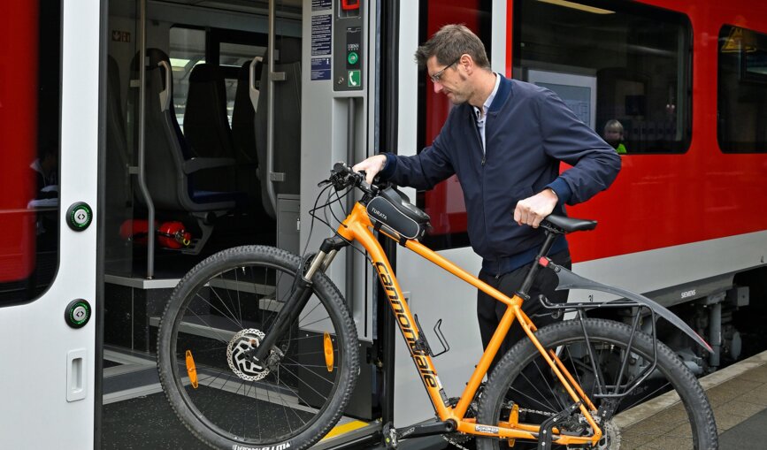 Mann steigt mit Fahrrad in eine S-Bahn