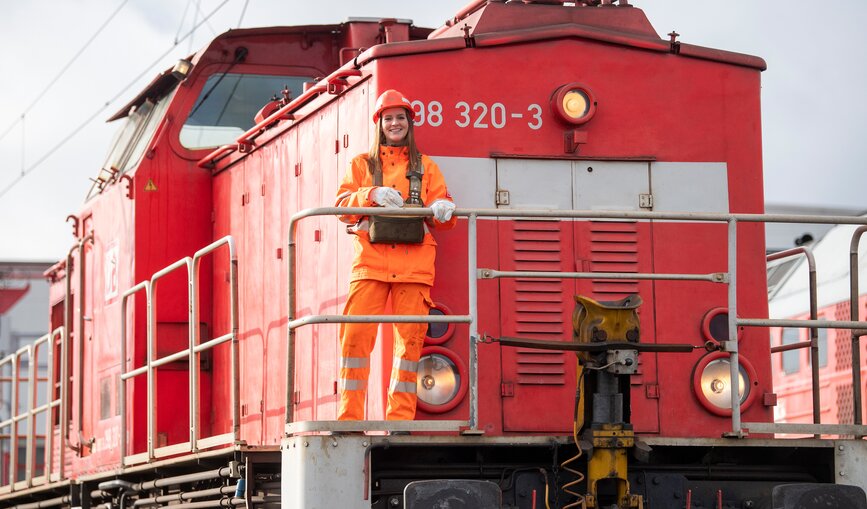 Eine junge DB Mitarbeiterin steht vor einer Lok