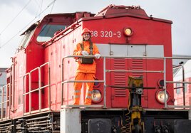 Eine junge DB Mitarbeiterin steht vor einer Lok