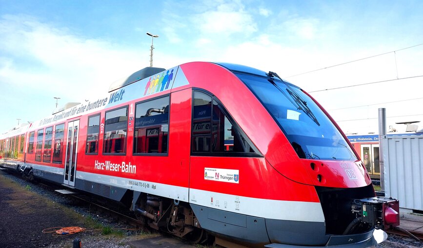 Der bunt folierte Regionalzug auf der Schiene