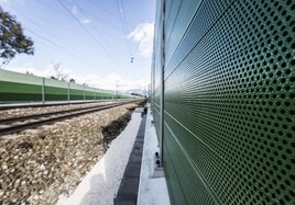 Eine grüne Lärmschutzwand entlang der Gleise
