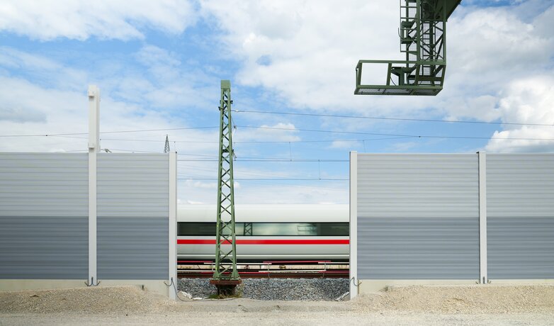 Eine Schallschutzwand an der Bahnstrecke im Bau mit einem vorbeifahrenden Zug. | © Deutsche Bahn AG / Oliver Lang