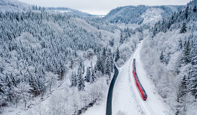 Ein Zug der DB Regio fährt durch eine Winterlandschaft.