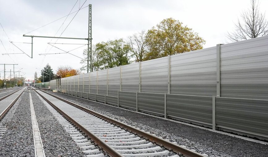 Eine graue Schallschutzwand neben der Bahnstrecke.
