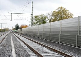 Eine graue Schallschutzwand neben der Bahnstrecke.