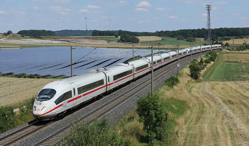 Zwei ICE 3 (Baureihe 403) fahren an einem Solarpark bei Hellmitzheim vorbei