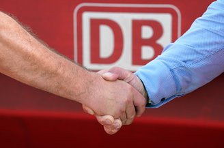 Ein Handschlag vor dem DB Logo. | © Deutsche Bahn AG / Volker Emersleben