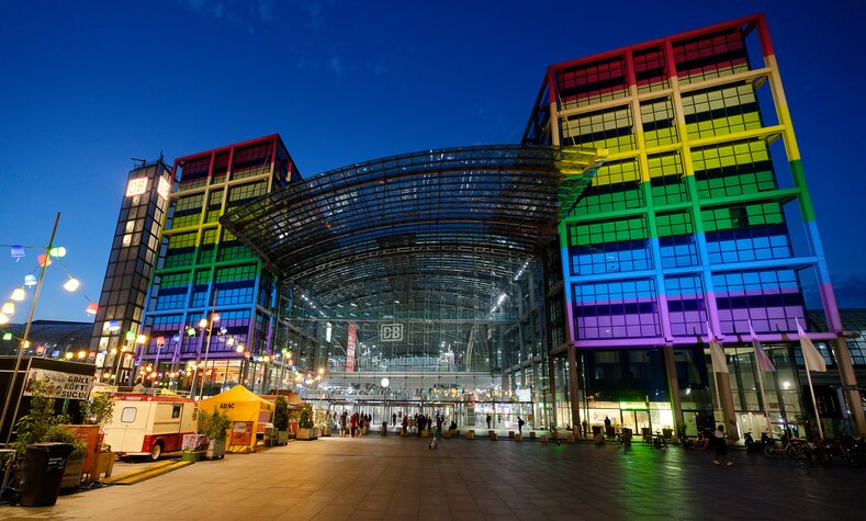 Der Berliner Hauptbahnhof leuchtet nachts in den Farben des Regenbogens.