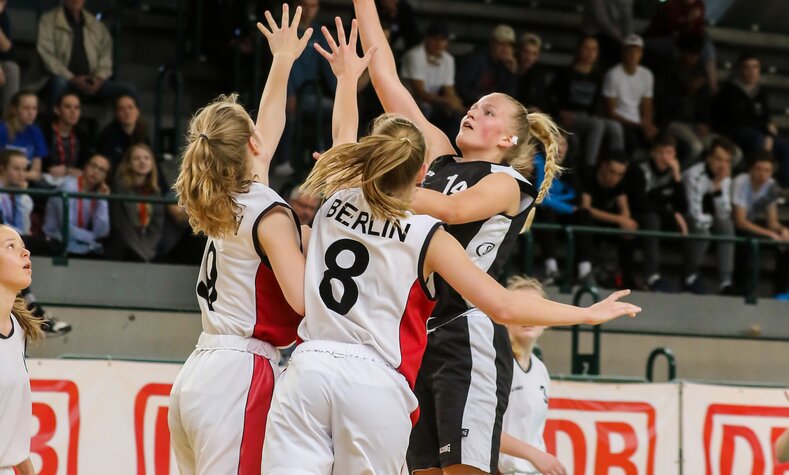Eine Gruppe junger Frauen spielt Basketball.