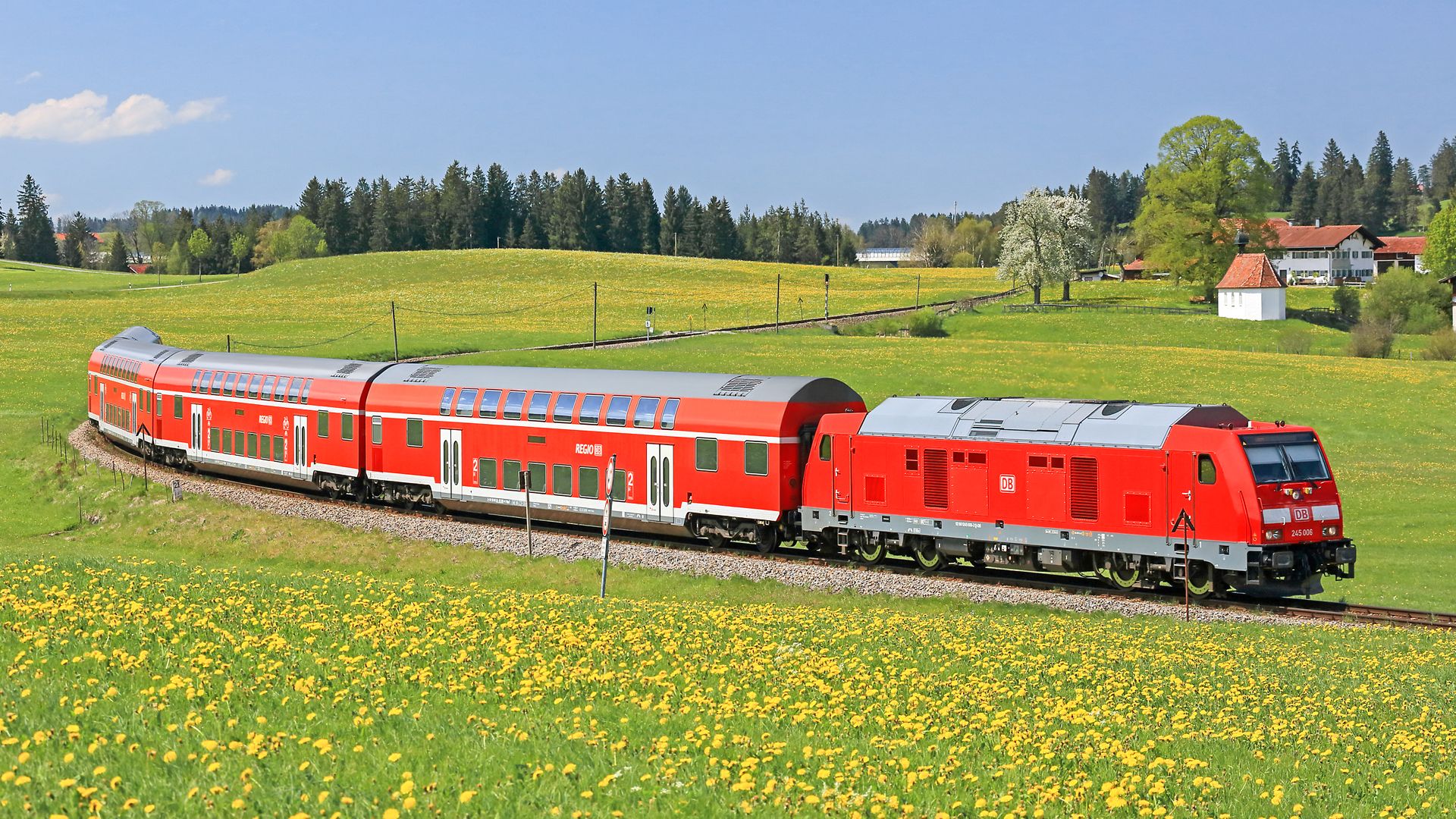 Ein Zug der Deutschen Bahn fährt durch eine blühende Landschaft.