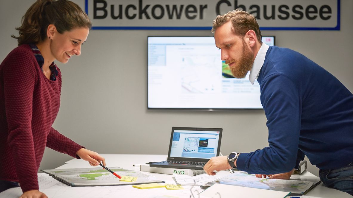 Zwei Mitarbeitende beraten sich an einem Schreibtisch.