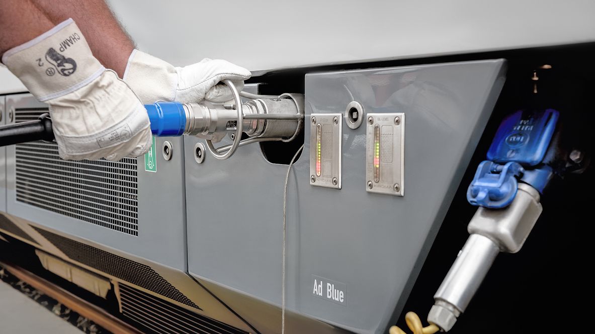 Eine Person mit Handschuhen betankt ein Schienenfahrzeug mit AdBlue 