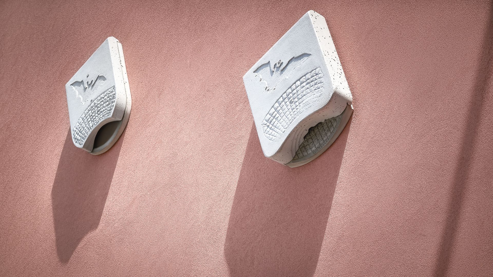 Zwei Behausungen für Fledermäuse sind an einer Häuserwand angebracht.