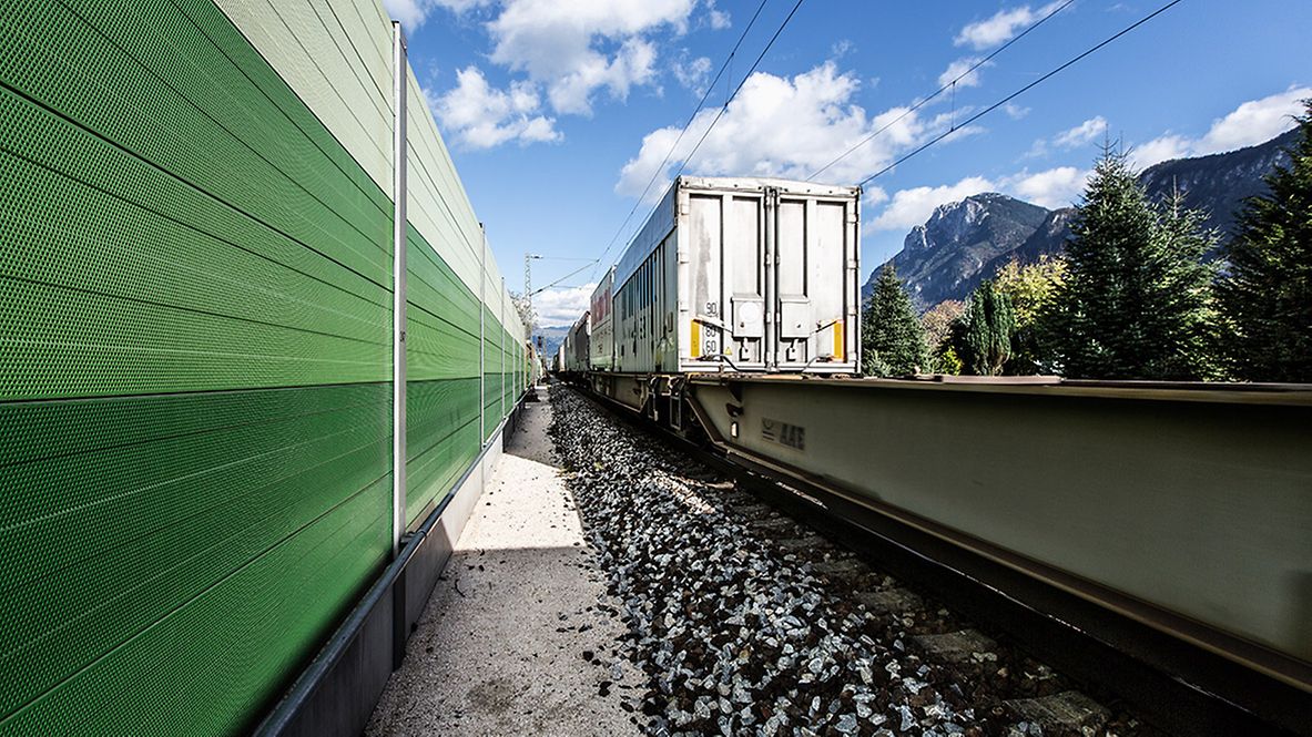Ein Güterzug fährt entlang einer Lärmschutzwand