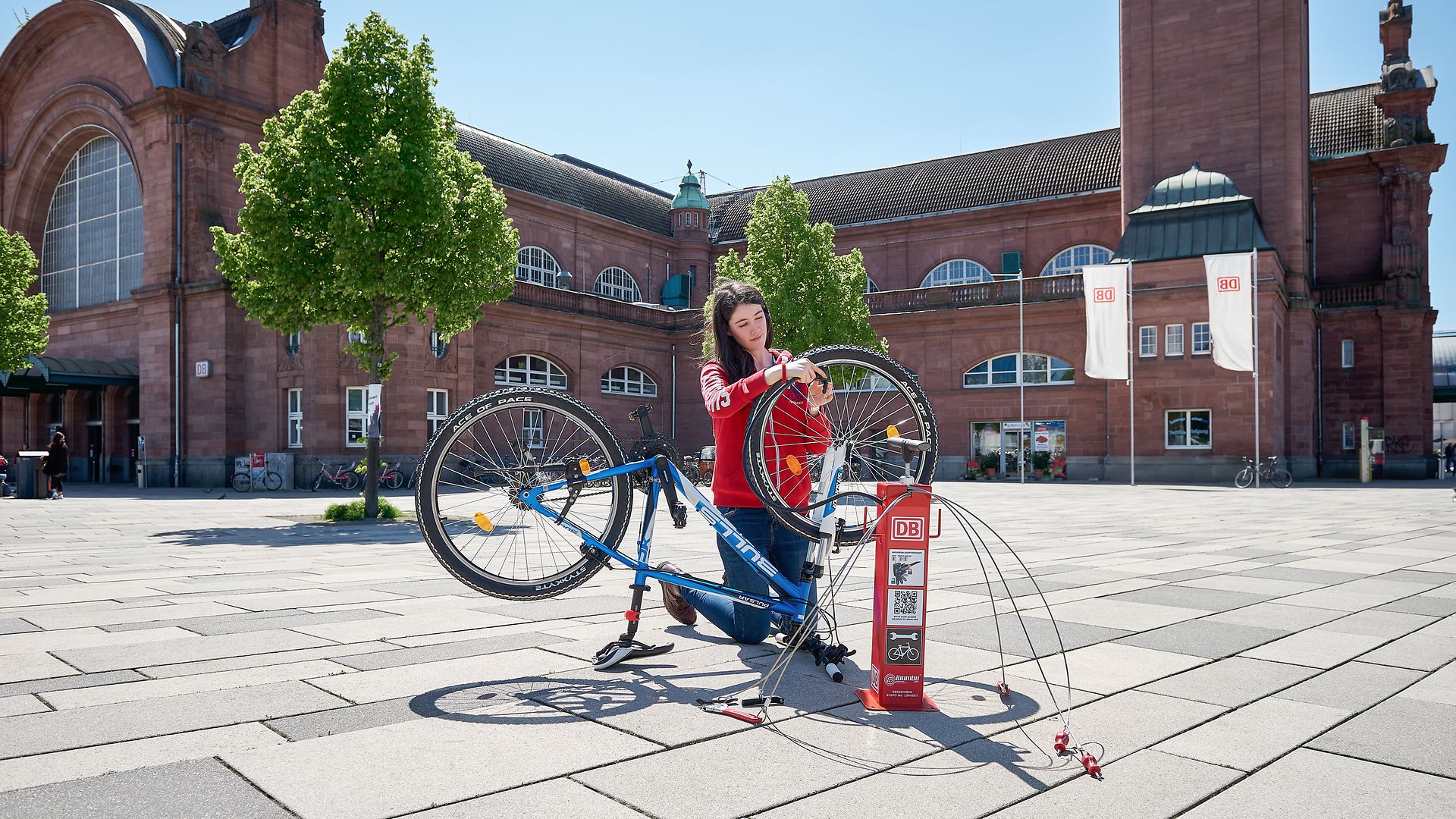 Eine Frau repariert auf dem Bahnhofsvorplatz ihr Rad an einer der mobilen Reparatursäulen. 