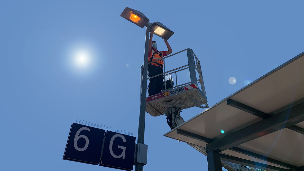 Ein Mitarbeiter rüstet eine Lampe a Bahnhof auf klimafreundliche LED-Leuchten um.
