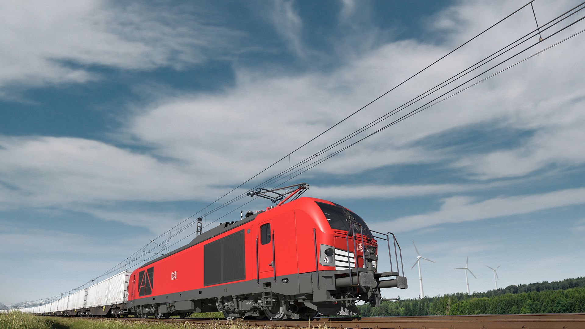 Eine rote Zweikraftlok fährt auf den Gleisen.