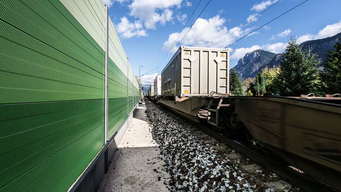 Eine grüne Schallschutzwand neben einem Güterwaggon