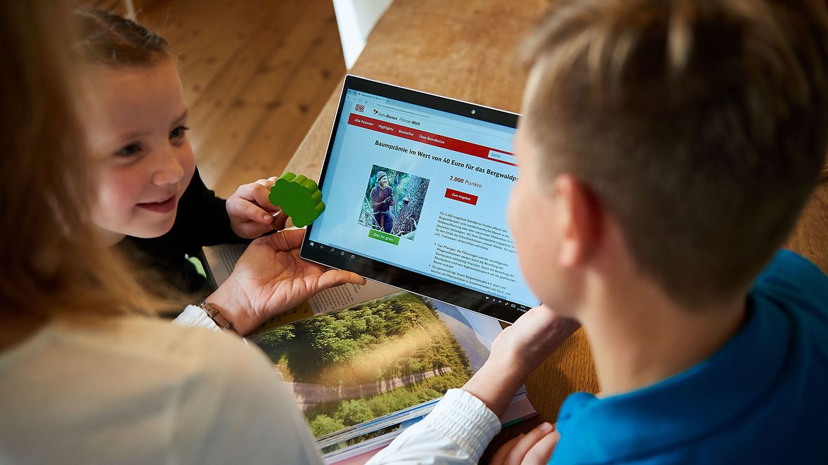 Eine Familie schaut sich auf dem Tablet die Produkte und Angebote der BahnBonus Prämienwelt an.