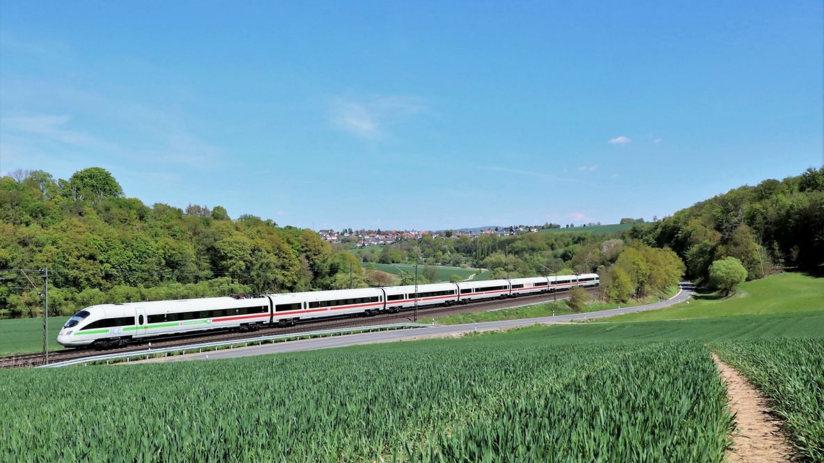 Ein ICE fährt durch eine grüne Landschaft.