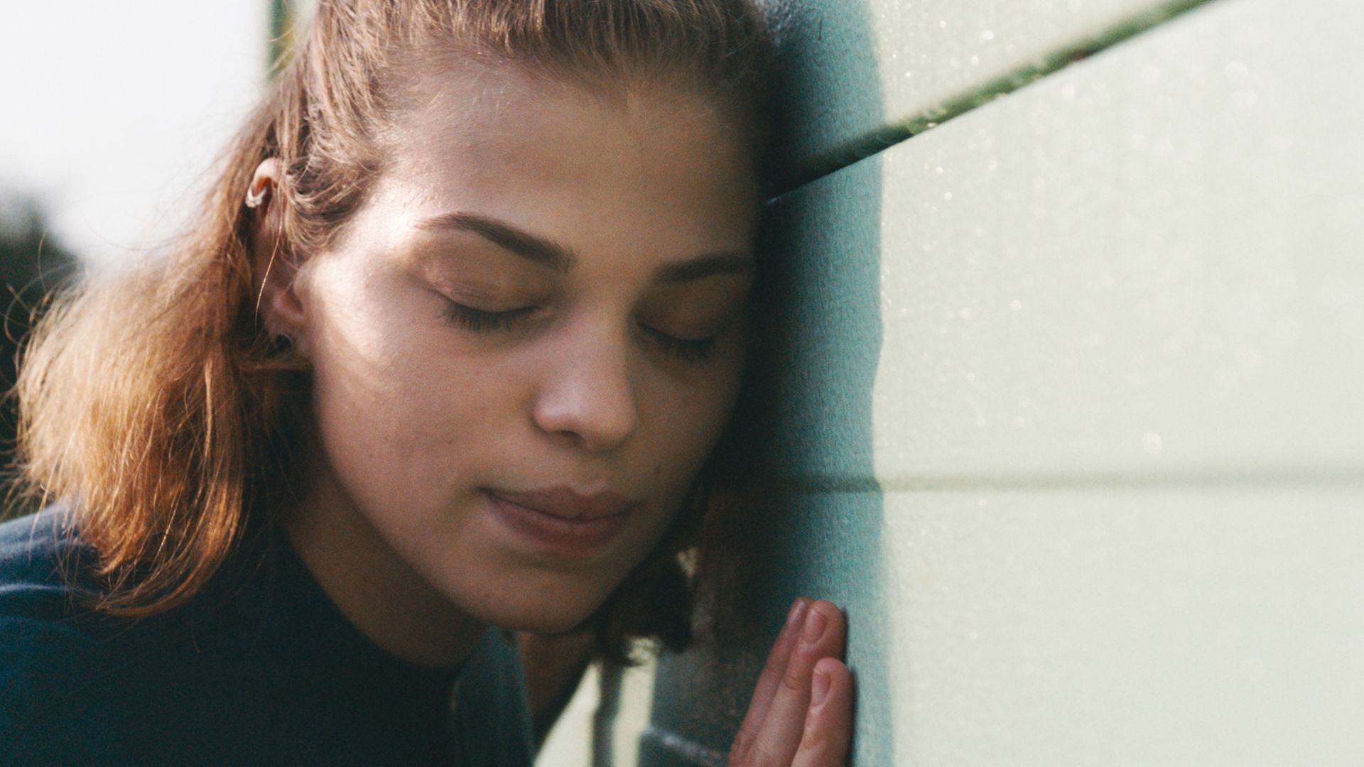 Eine Frau lauscht an einer Schallschutzwand.