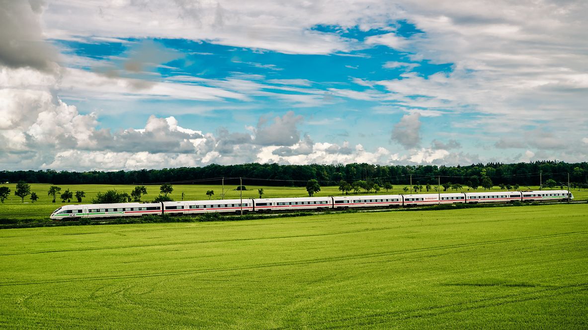 Ein ICE fährt in grüner Natur.