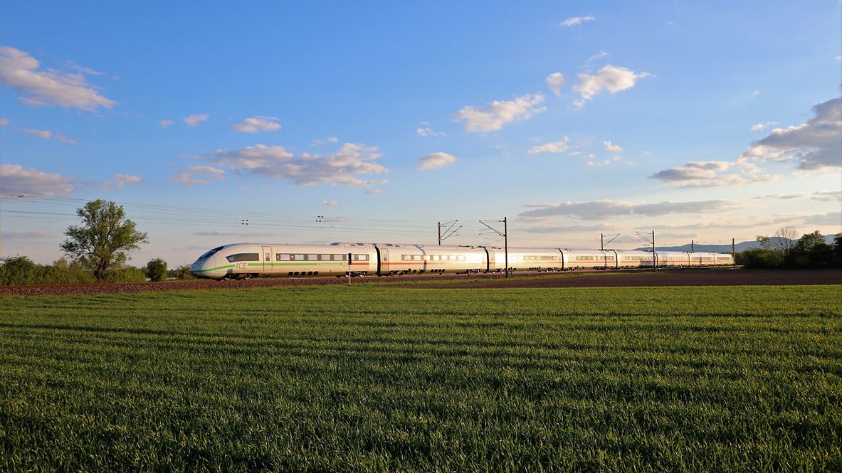 Ein Zug fährt durch eine grüne Landschaft.